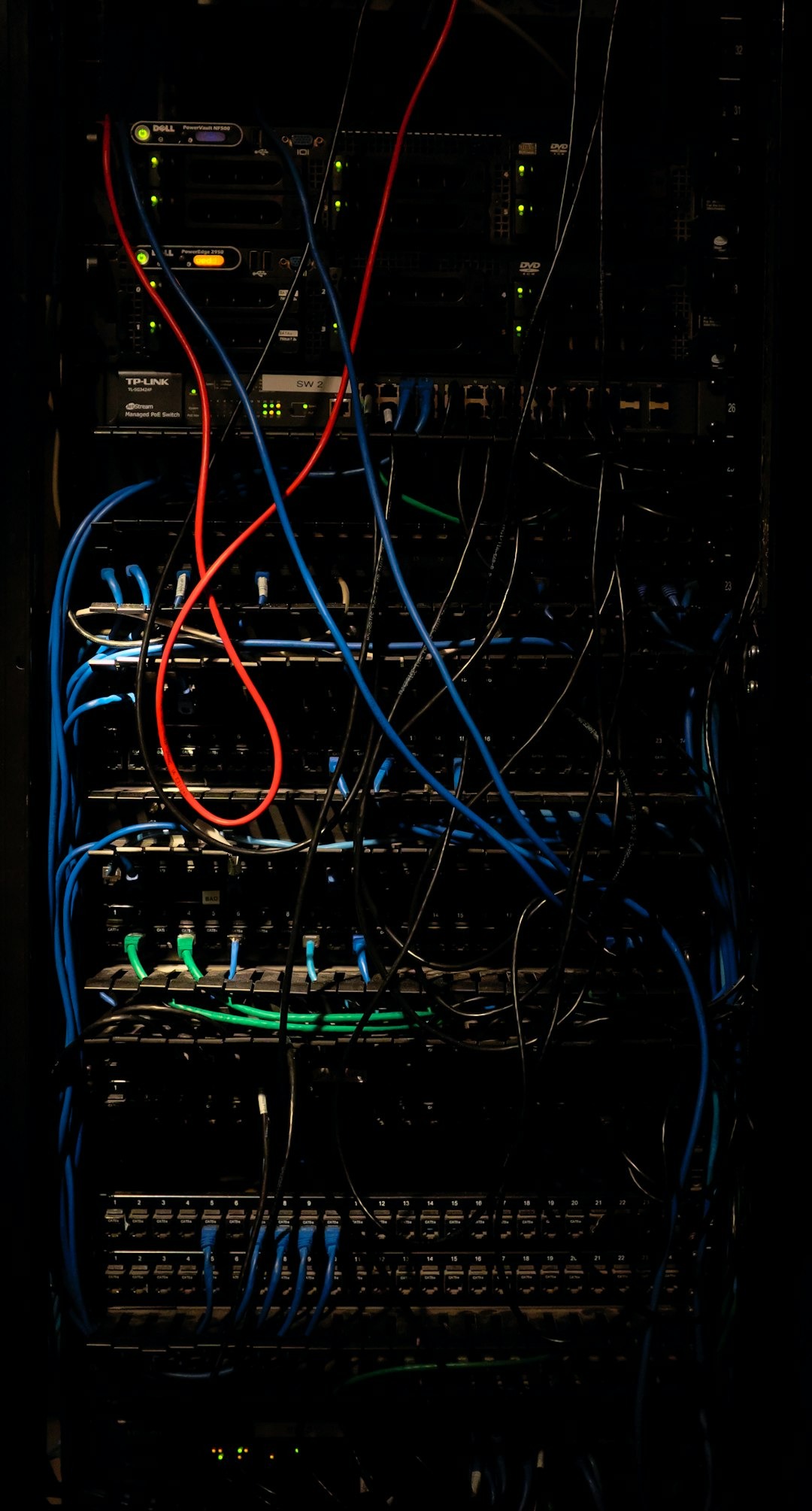 Server rack with tangled blue and red network cables.